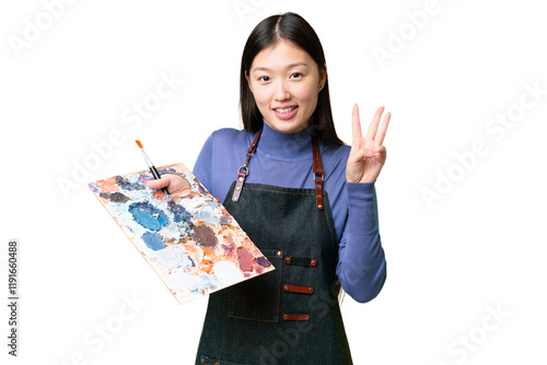 Young artist woman holding a palette over isolated chroma key background happy and counting three with fingers