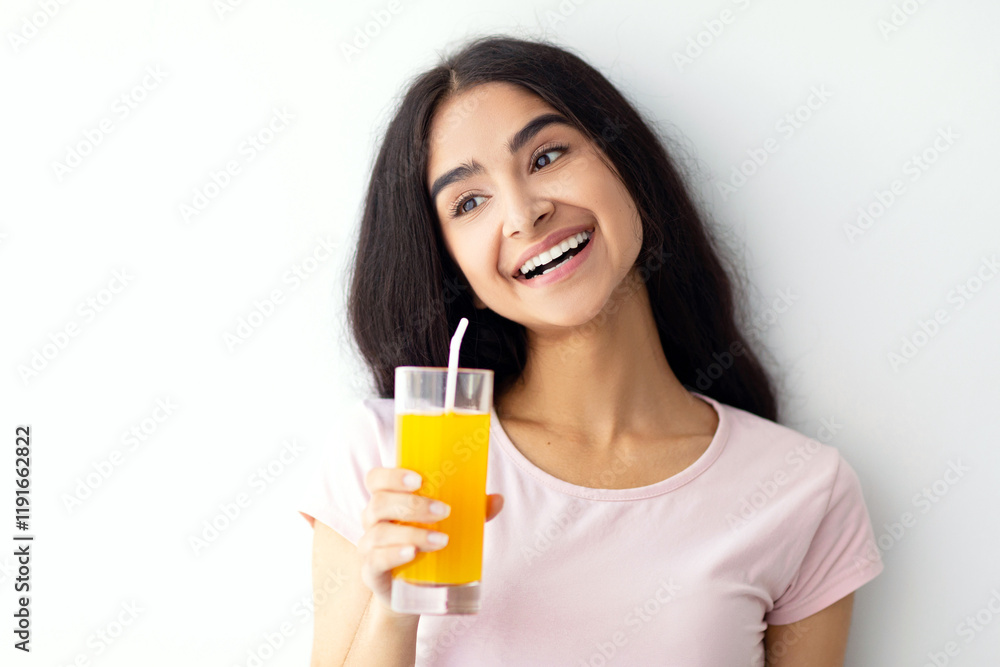 Summer detox and healthy eating concept. Smiling Indian woman with glass of fresh orange juice against white wall. Positive Eastern lady enjoying her delicious fruit drink Summer detox and healthy eating concept. Smiling Indian woman with glass of fresh orange juice against white wall. Positive Eastern lady enjoying her delicious fruit drink