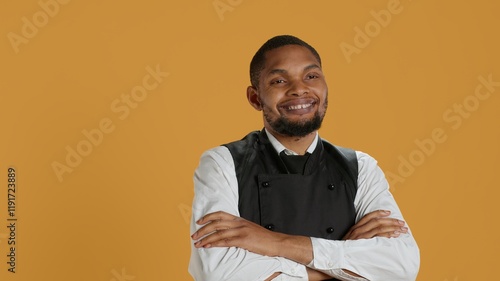 Portrait of professional server posing with confidence with arms crossed in studio, wearing his five star restaurant uniform and serving clients. Waiter with customer focused duty. Camera A. photo