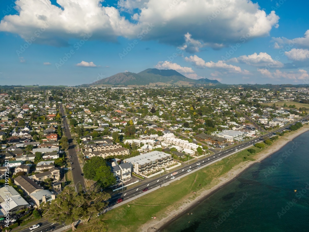 Fototapeta premium Aerial view of a Taupo, with residential areas, apartments, and a beach. Sunny day, people relaxing on the beach. LAKE TAUPO, TAUPO, WAIKATO, NEW ZEALAND