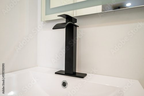 Modern black faucet on a white sink. Sleek design for a contemporary bathroom. photo