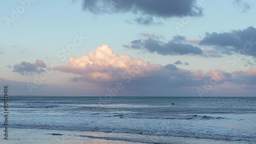Ocean with gentle waves under a partly cloudy sky. Clouds have pink and orange tones, probably due to the sunset in Uruguay department of Rocha.