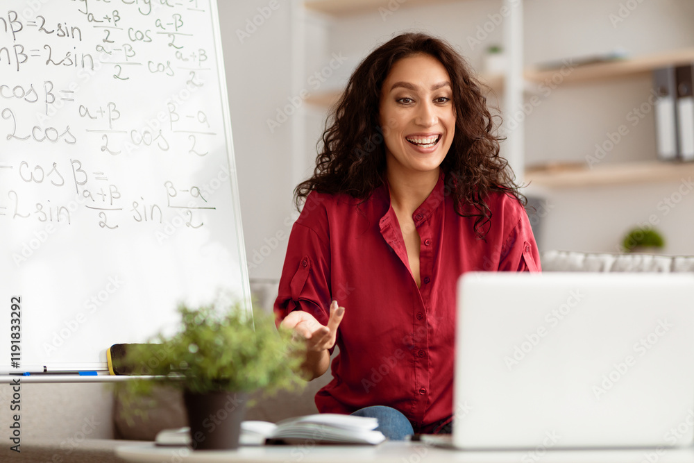 E-Learning Concept. Smiling lady math teacher talking, explaining trigonometric functions to students on videocall. Excited woman looking at laptop screen, sitting at desk E-Learning Concept. Smiling lady math teacher talking, explaining trigonometric functions to students on videocall. Excited woman looking at laptop screen, sitting at desk