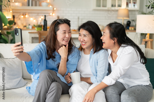 Happy group Asian middle-aged women smile take a selfie in home living room.Happiness lifestyle group of Asian mature adult friendship reunion having a great party at home.friendship reunion concept.