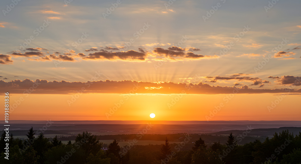 The serene atmosphere of a summer evening is enhanced by a sky filled with golden and amber brilliance.