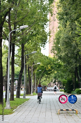 Obraz na płótnie This photo showcases NTU’s thoughtful pathway design with clearly marked pedestrian and bike lanes. By prohibiting cars, NTU creates a peaceful and green campus that prioritizes safety and environment w salonie
