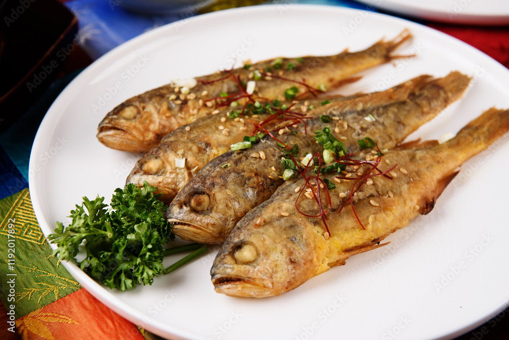 Four grilled fish on a white round plate Four grilled fish on a white round plate