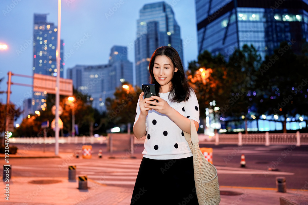Obraz premium Young Woman Using Mobile Phone in Vibrant Cityscape at Dusk