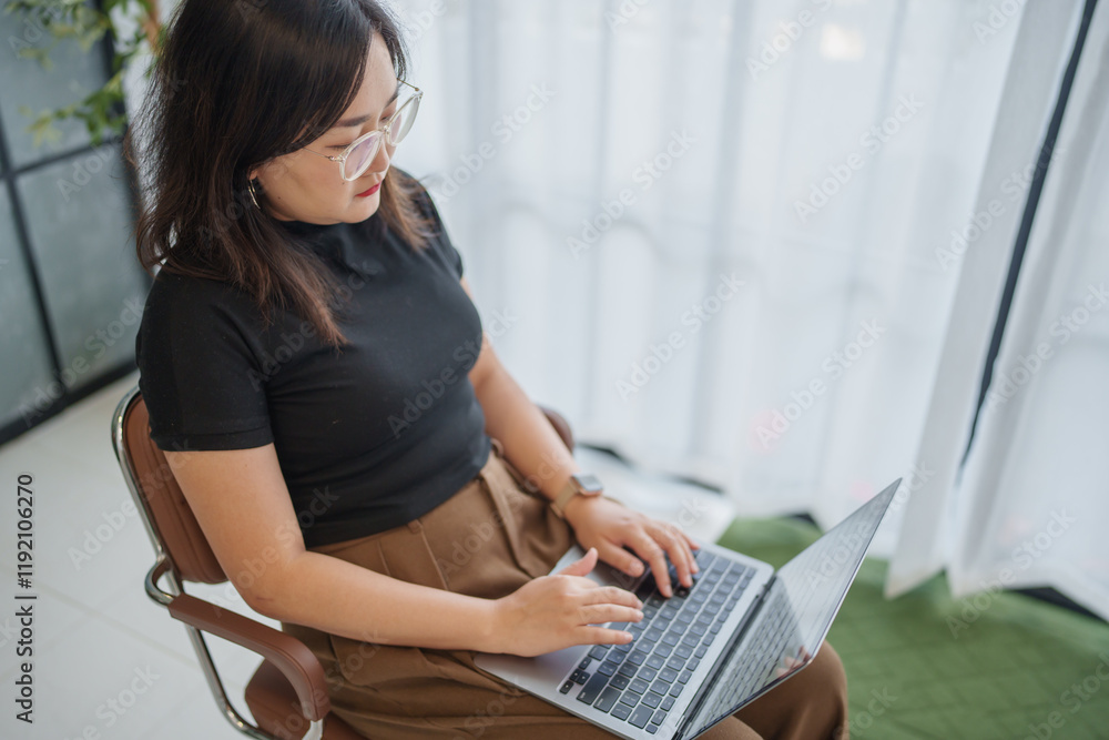 Naklejka premium concentrated Asian woman using laptop computer creative girl working and typing on keyboard