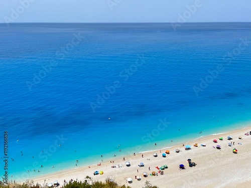 Egremni beach, Lefkada, Greece. Rich, deep blue, crystal clear water and pure white sand with colourful beach umbrellas and people swimming. 