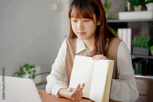 Asian woman using laptop to study student engaged in online learning at college photo