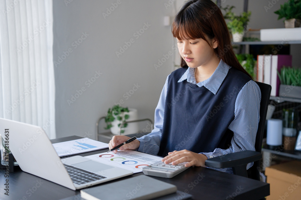 Asian businesswoman doing paper work with pen laptop calculator Asian businesswoman doing paper work with pen laptop calculator