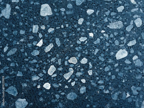 A close-up of a terrazzo floor with a dark blue base and variously sized white and light blue aggregate pieces, creating a speckled, textured pattern. Perfect for modern interior designs