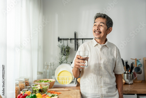 Asian senior mature man drinking a glass of water in kitchen at home.