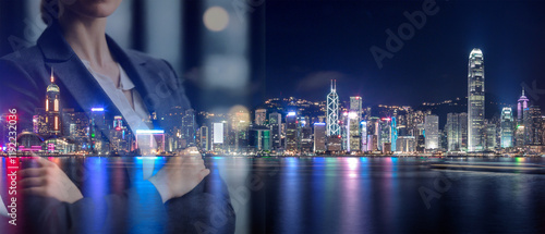 A woman in a business suit stands before a vibrant Hong Kong nightscape, symbolizing ambition and success in a global city. photo