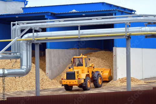 Obraz na płótnie Front loader operating in woodchip storage yard at manufacturing facility. Bulldozer handling woodchips, transporting wood chips at an warehouse, storage operations for pellets manufacturing. Biofuel w salonie
