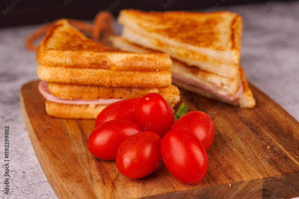Savory Ham and Cheese Sandwich and Cherry Tomatoes on a Dark Cutting Board Savory Ham and Cheese Sandwich and Cherry Tomatoes on a Dark Cutting Board