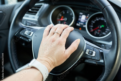 Close-up of a woman's hand on the steering wheel.
A woman presses the horn on the steering wheel of a car. photo