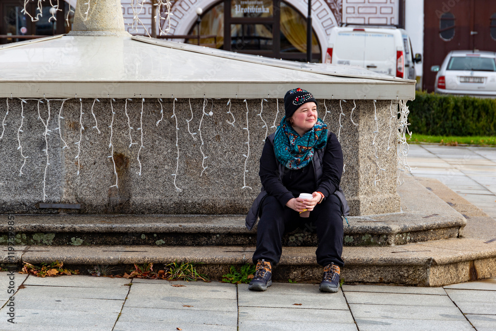 A woman sitting on the steps near a fountain.