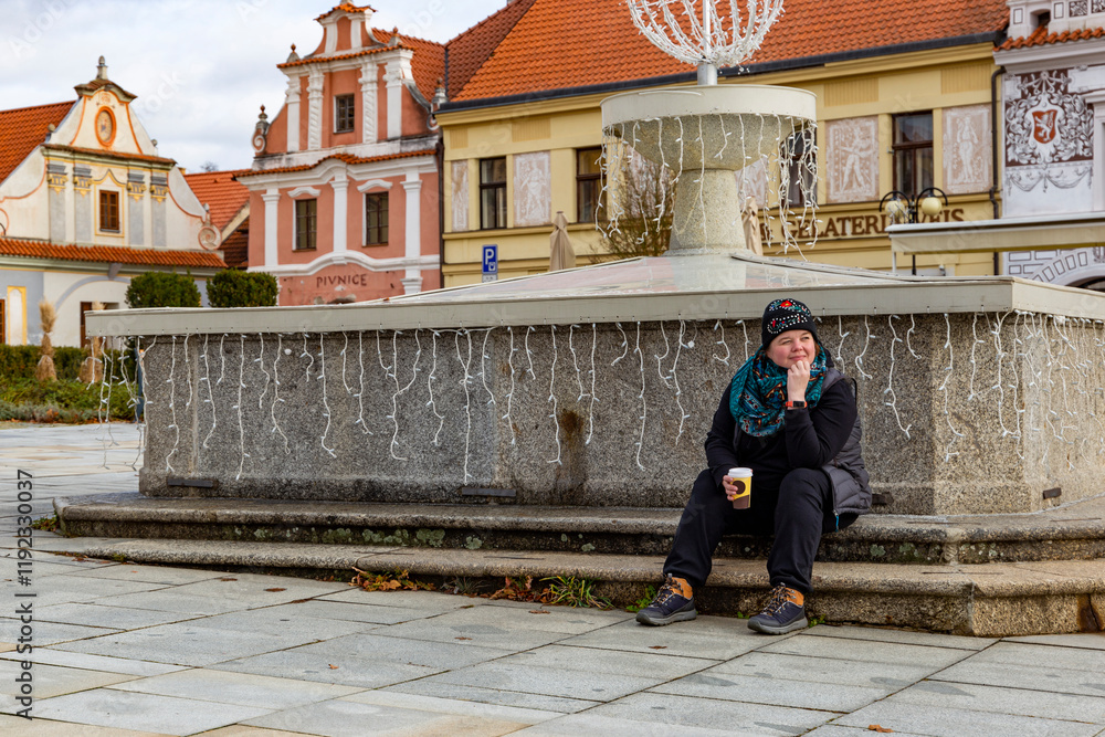 A woman sitting on the steps near a fountain.