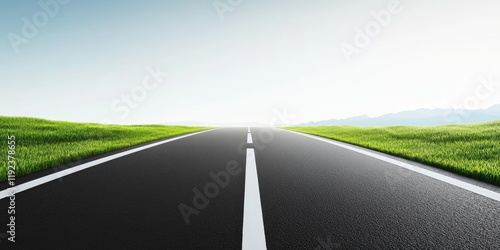 Empty asphalt road vanishing into bright horizon with green grass.