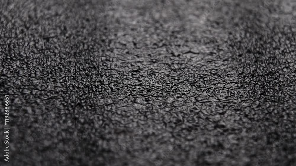 A sheet of black layered polystyrene foam material falling in slow motion on textured wood surface A sheet of black layered polystyrene foam material falling in slow motion on textured wood surface