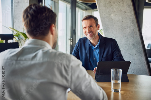 Smiling businessman taking interview of candidate at desk in office