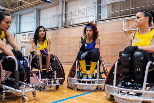 People sitting in wheelchair and discussing at rugby sports center photo