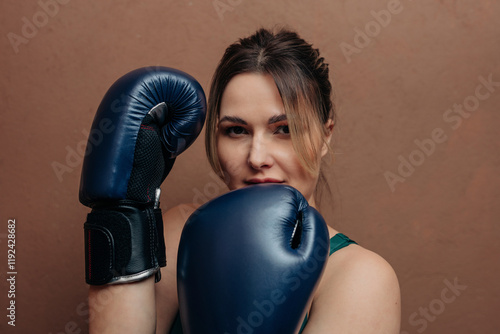 Woman posing with boxing gloves against brown background photo