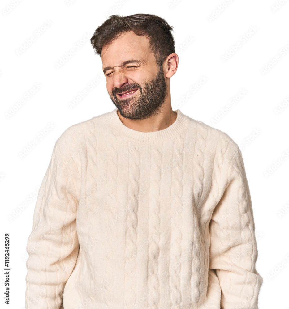 Fototapeta premium Studio portrait of young Hispanic male laughs and closes eyes, feels relaxed and happy.