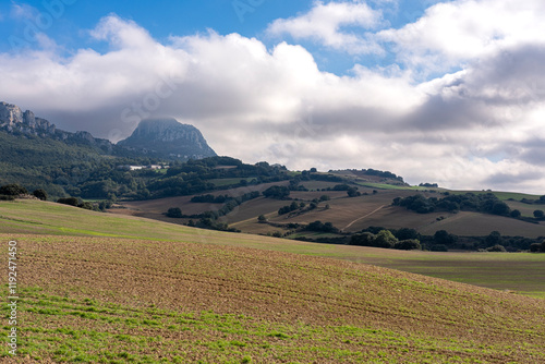 A breathtaking view of rolling hills beneath a partly cloudy sky, showcasing lush greenery and the grandeur of the mountain backdrop. Perfect for nature lovers. photo