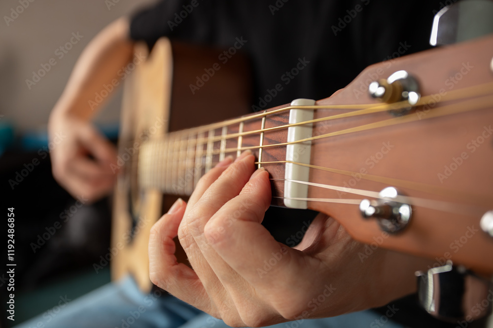 Fototapeta premium Hand Playing Acoustic Guitar Close-Up, musician sitting indoor, leisure strumming, practice of chords