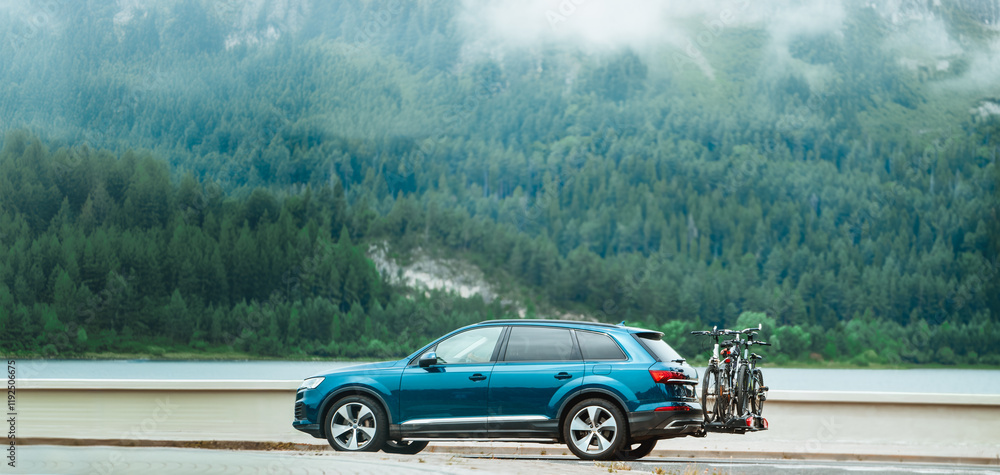 Fototapeta premium SUV with bikes on back driving past lake
