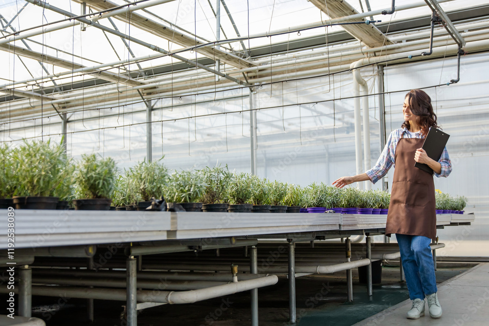 Glasshouse supervisor checking the plants and making notes Glasshouse supervisor checking the plants and making notes