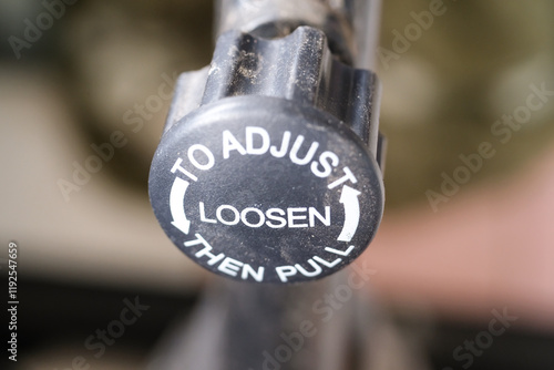 Closeup of a knob on a bicycle frame. The knob is used to adjust the seat height on a bicycle. The knob is black plastic with white text instructions. Bicycle accessories photo