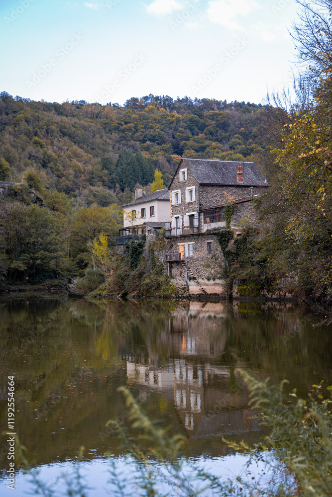 Riverside Stone House with Reflections on the Lot River in Estaing, Occitania, France Riverside Stone House with Reflections on the Lot River in Estaing, Occitania, France