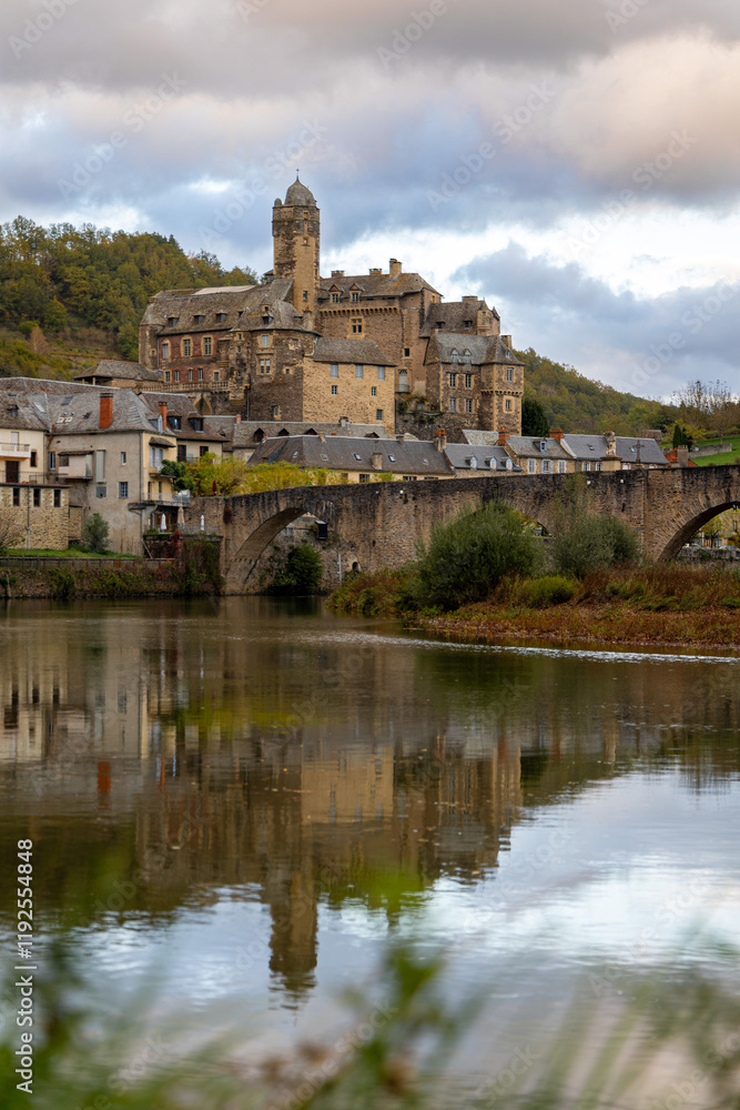 Panoramic View of Estaing Village and Castle with Reflections on the Lot River, Occitania, France Panoramic View of Estaing Village and Castle with Reflections on the Lot River, Occitania, France