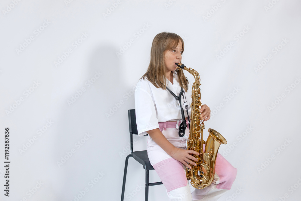 Naklejka premium Girl playing, practicing the saxophone, playing a melody on a musical instrument, sitting on black chair on white background. Out-of-school children activities, lessons