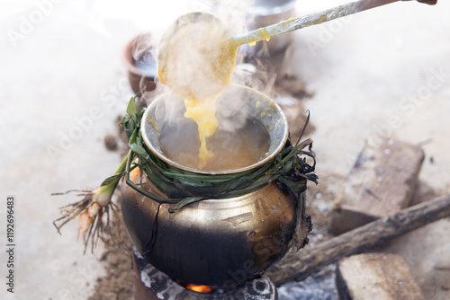 celebrating Traditional Thai Pongal festival to sun god with pot, lamp,wood fire stove, fruits and sugarcane. Making Sakkarai or sugar pongal and ven pongal in sand stove in traditional method. photo