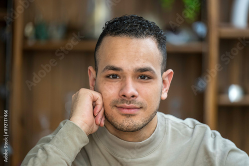 Smiling young adult man resting his face on his hand, with a blurred background, Netherlands photo