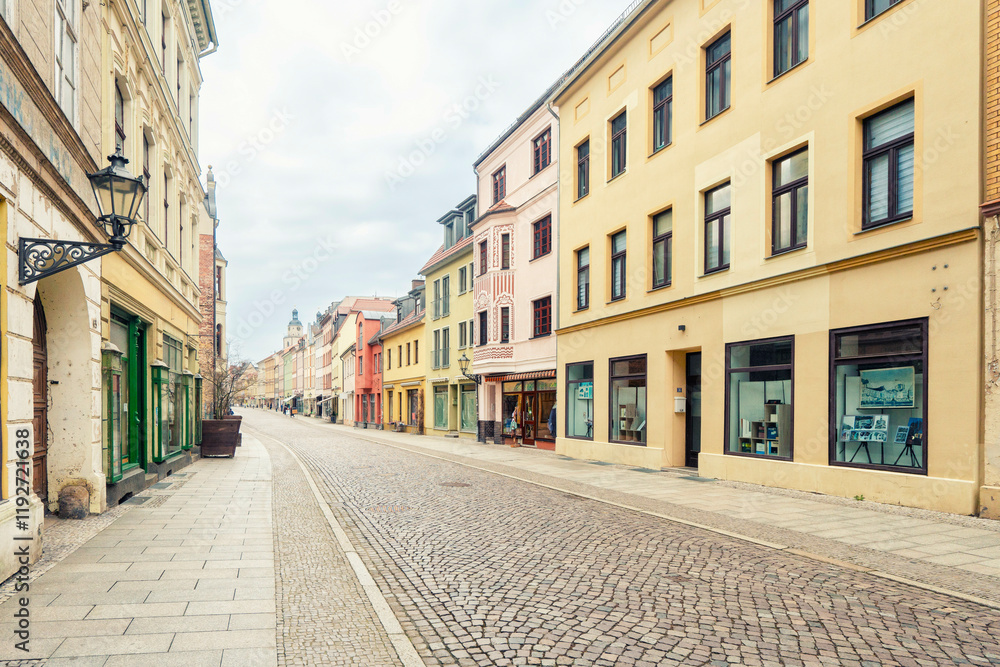 A quiet street lined with colorful buildings, cobblestone pavement, and a solitary pedestrian old city, Luther Stadt Wittenberg, Germany A quiet street lined with colorful buildings, cobblestone pavement, and a solitary pedestrian old city, Luther Stadt Wittenberg, Germany