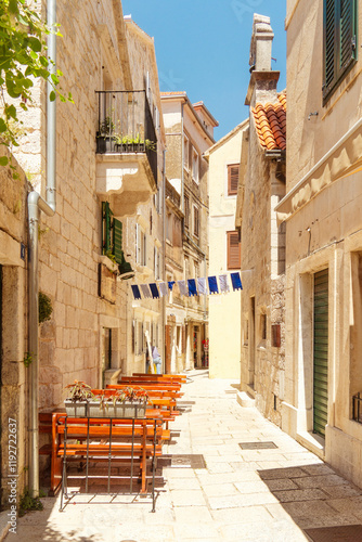 Narrow cobblestone street with outdoor cafe seating in a quaint Omis old town, Croatia photo