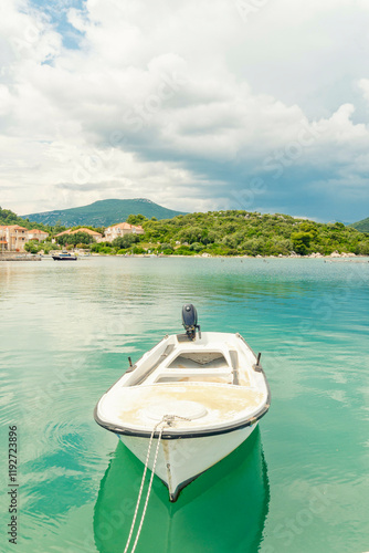 Boat anchored to a dock with lush green backgrop and mountains in the back ground and turquoise blue water of the Adriatic sea, Mali Ston, Croatia photo