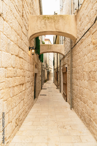 Narrow cobblestone alleyway with stone walls and arch in the historical city of Omis, Croatia photo