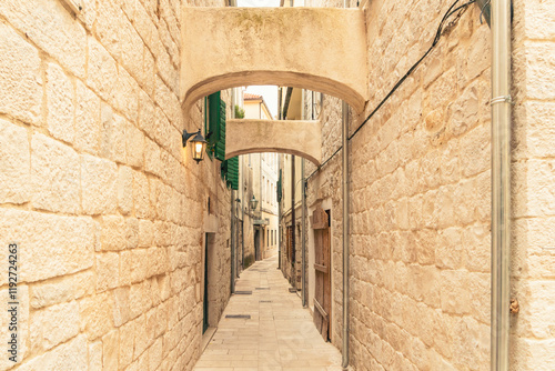 Narrow cobblestone alleyway with stone walls and arch in the historical city of Omis, Croatia photo