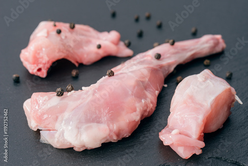 Fresh raw rabbit meat with peppercorns on dark stone photo