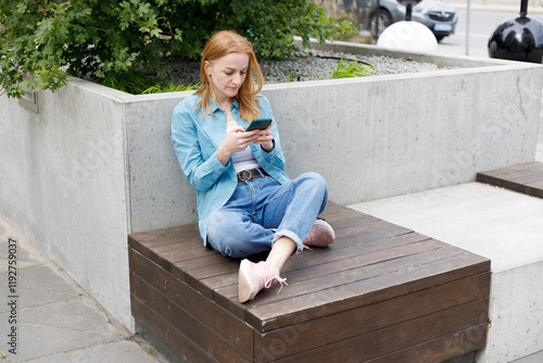 Woman Using Smartphone Outdoors in Warsaw Urban Park photo