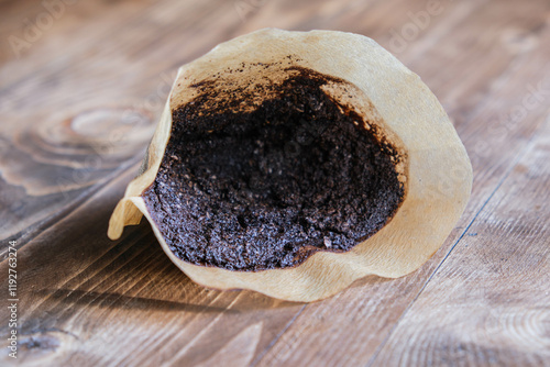 Used cone coffee filter on a wooden table, used ground coffee in a filter