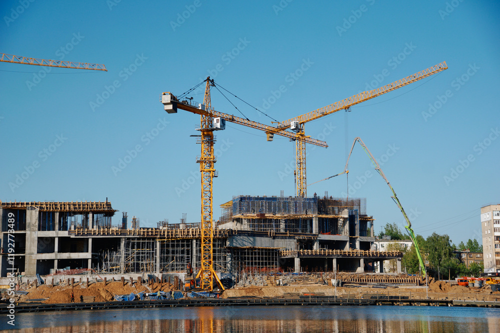 cranes at the construction site , construction of a large building on the city embankment , urbanization cranes at the construction site , construction of a large building on the city embankment , urbanization