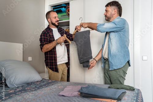 Gay couple sharing a moment while organizing clothes at home photo